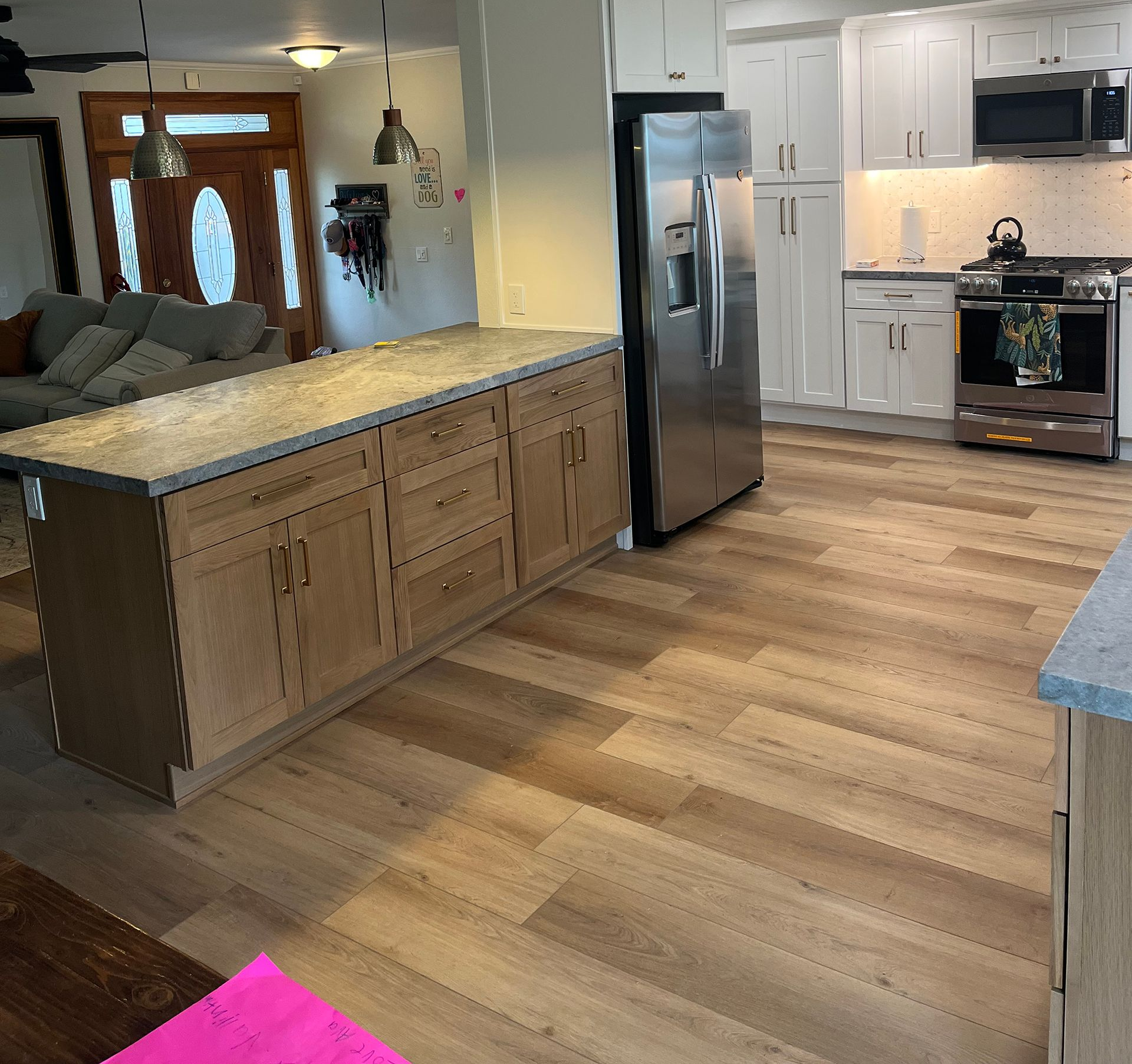 Kitchen with island, light wood cabinets, stainless steel appliances, and wood-look flooring.