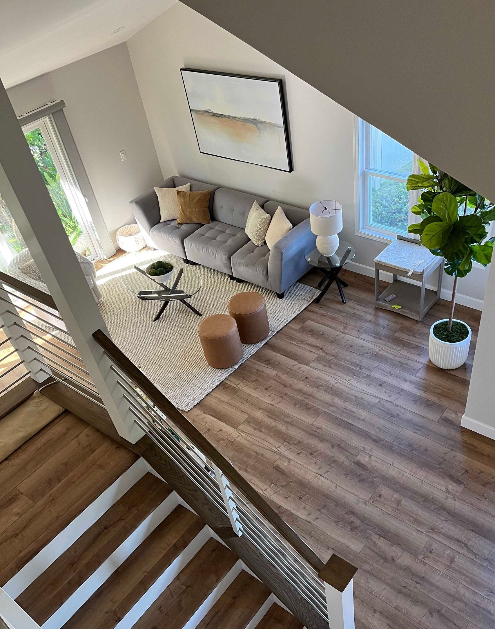 A modern living room with gray couch, coffee table, and area rug, viewed from a staircase.