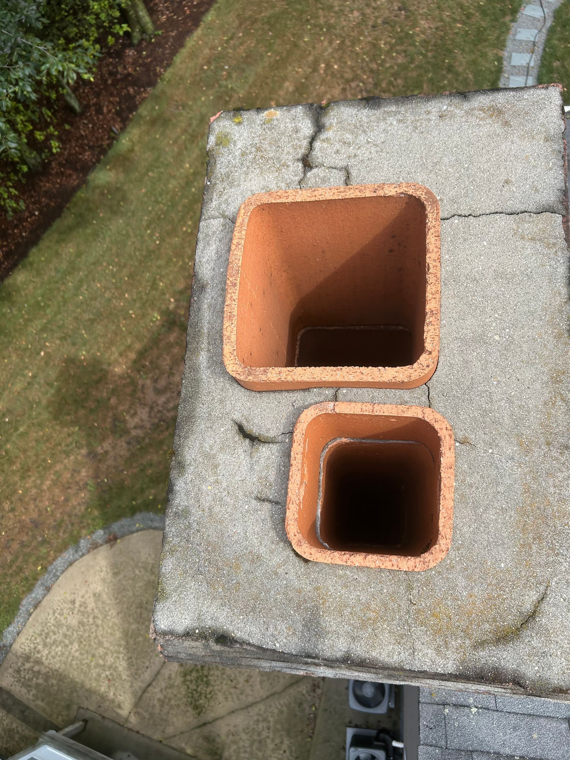 Two orange brick chimney flues on a gray concrete rooftop