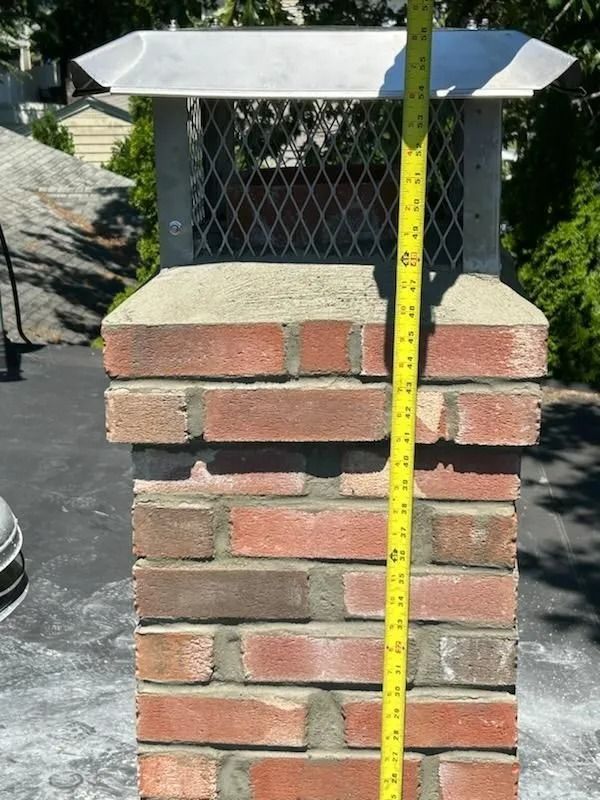 Brick chimney with metal cap, a yellow tape measure is held next to it.