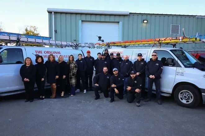 Group of people posing with service vans in front of a building.
