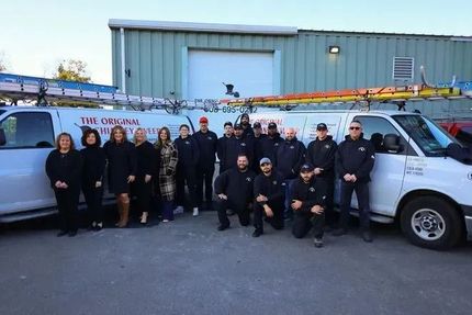 Group of people posing with service vans in front of a building.