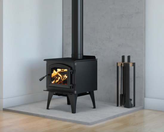 Black wood-burning stove with a fire burning, set on a light tiled hearth against a gray wall.