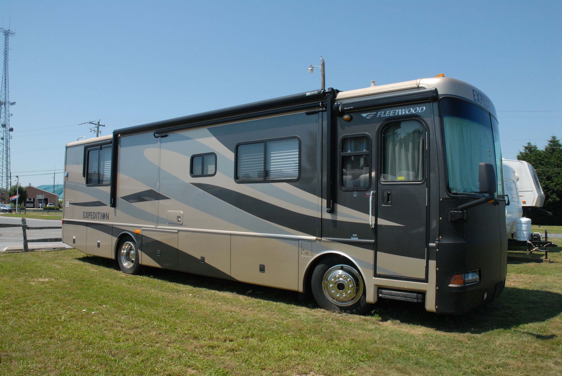 Silver and black RV parked on grass under a clear sky