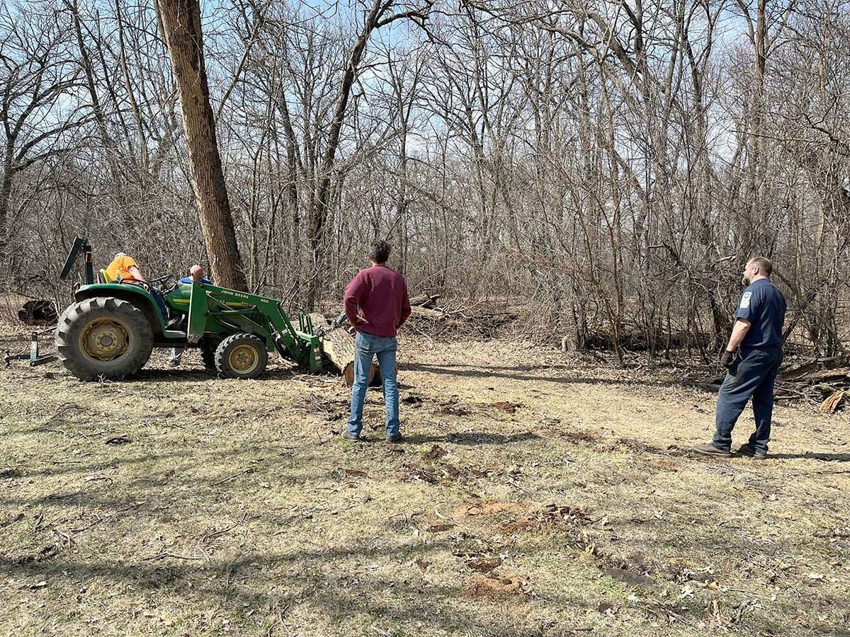 Tractor, two men, and a tree line clearing