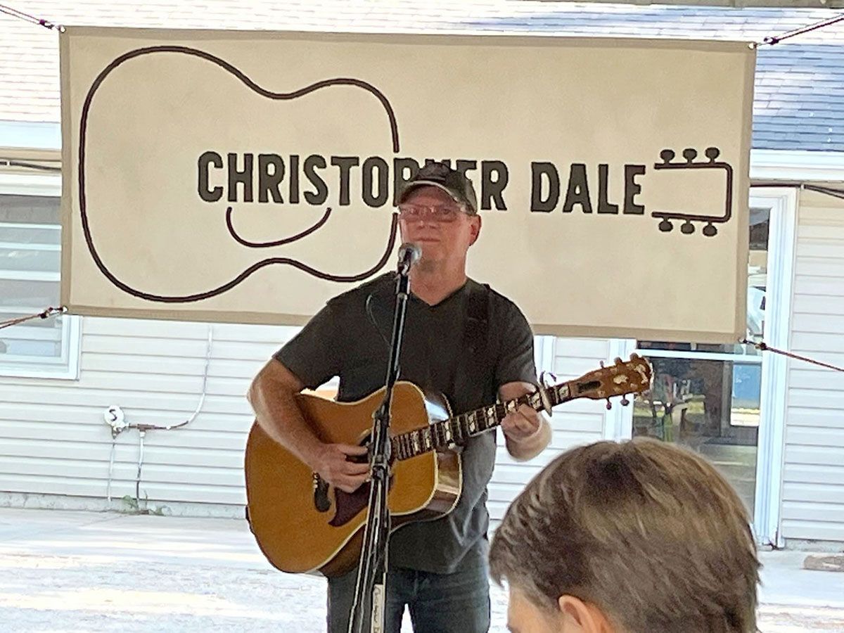 Man playing acoustic guitar, singing at outdoor event