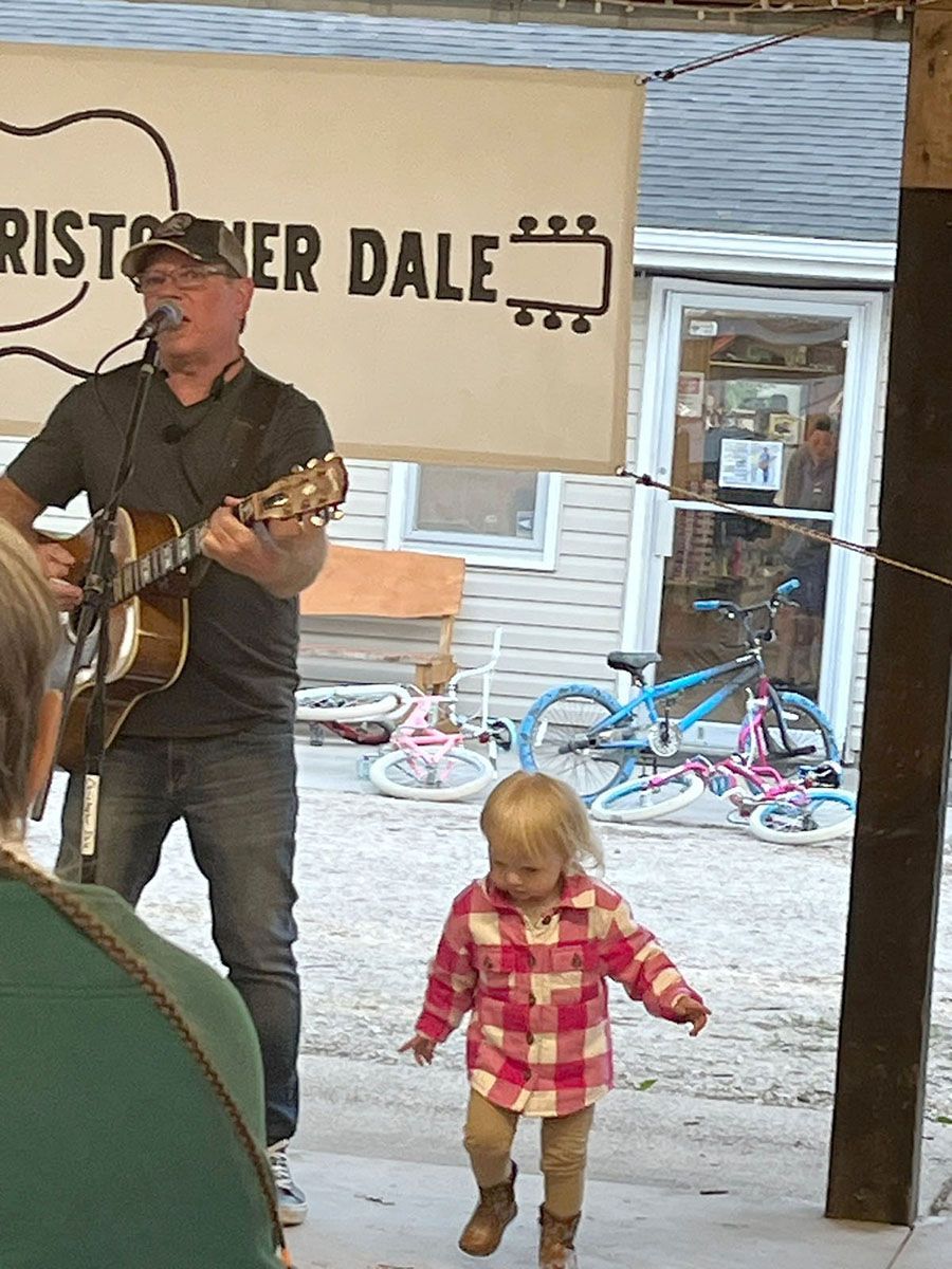 Man playing guitar and singing; a child dances nearby