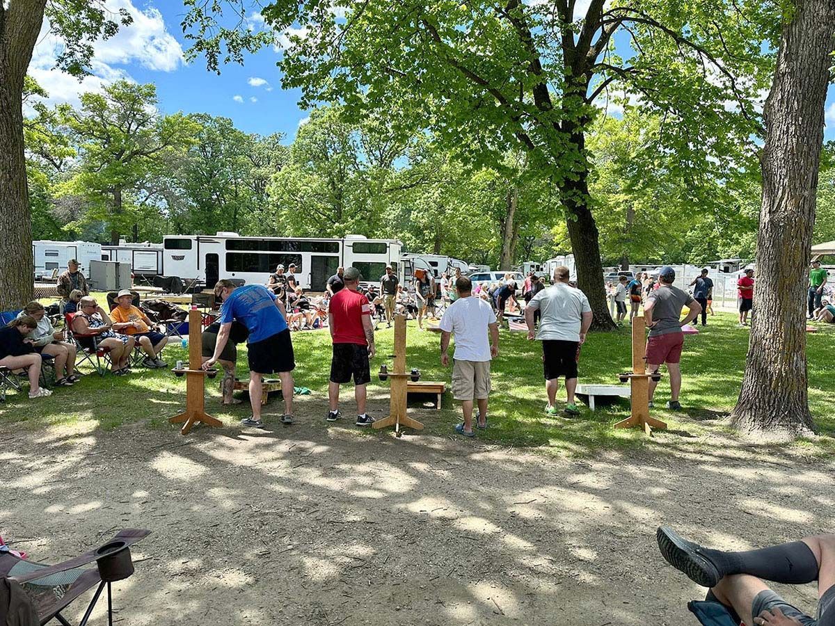 People playing a lawn game outdoors near trailers