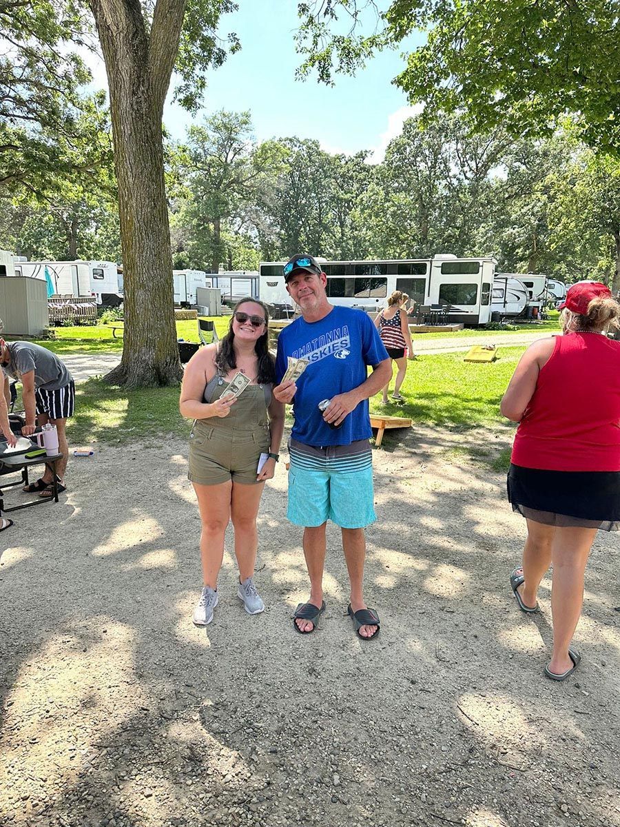 Woman and man standing outside, holding prizes; RV park setting