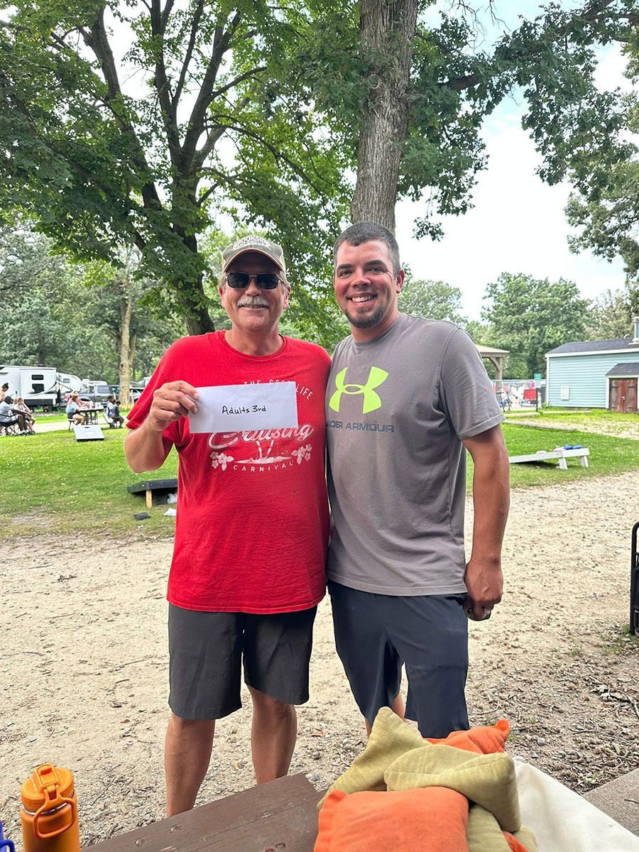 Two men outdoors; one holding a paper