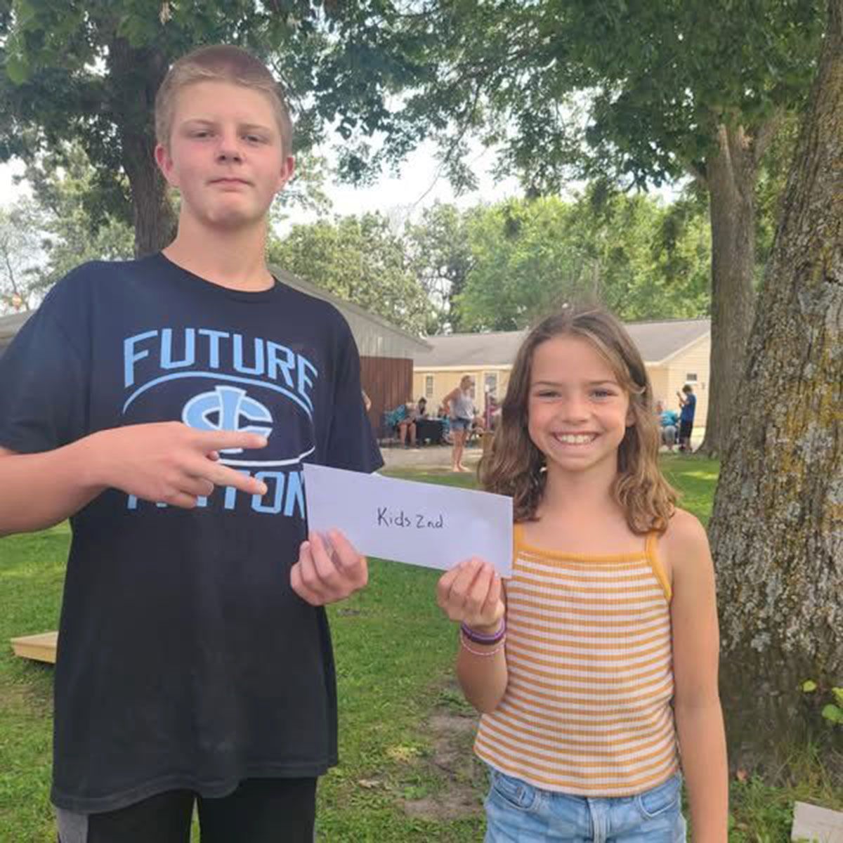 A boy and a girl holding a paper, outside