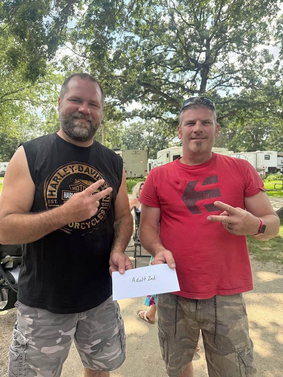 Two men outdoors, one holding a paper