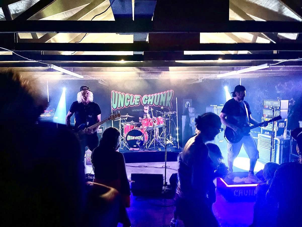 A ban performs on stage, backlit by blue lights