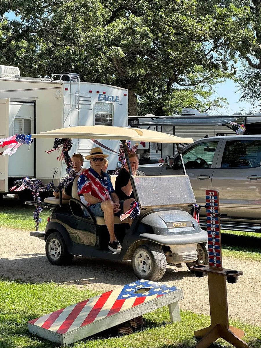 People in a decorated golf cart near a camper