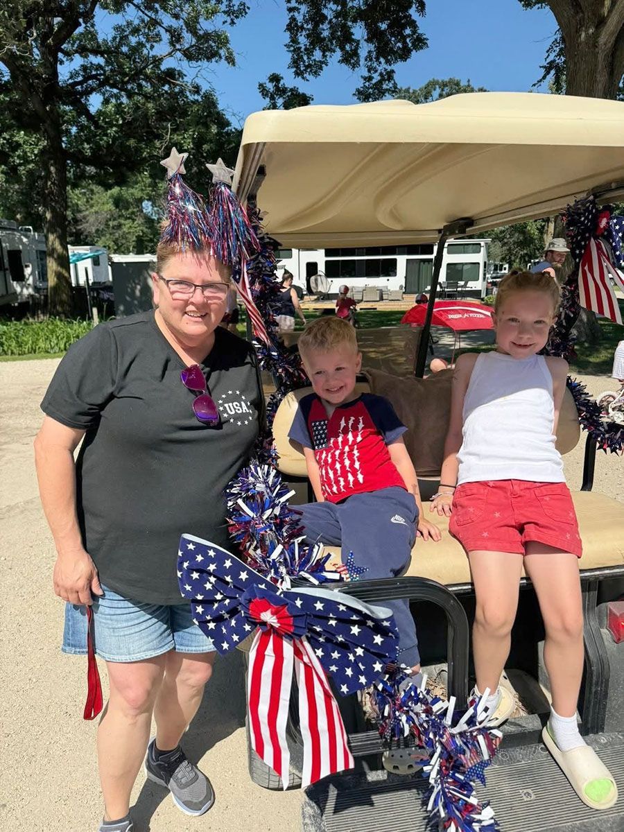 Woman and two children pose with a patriotic-decorated golf cart