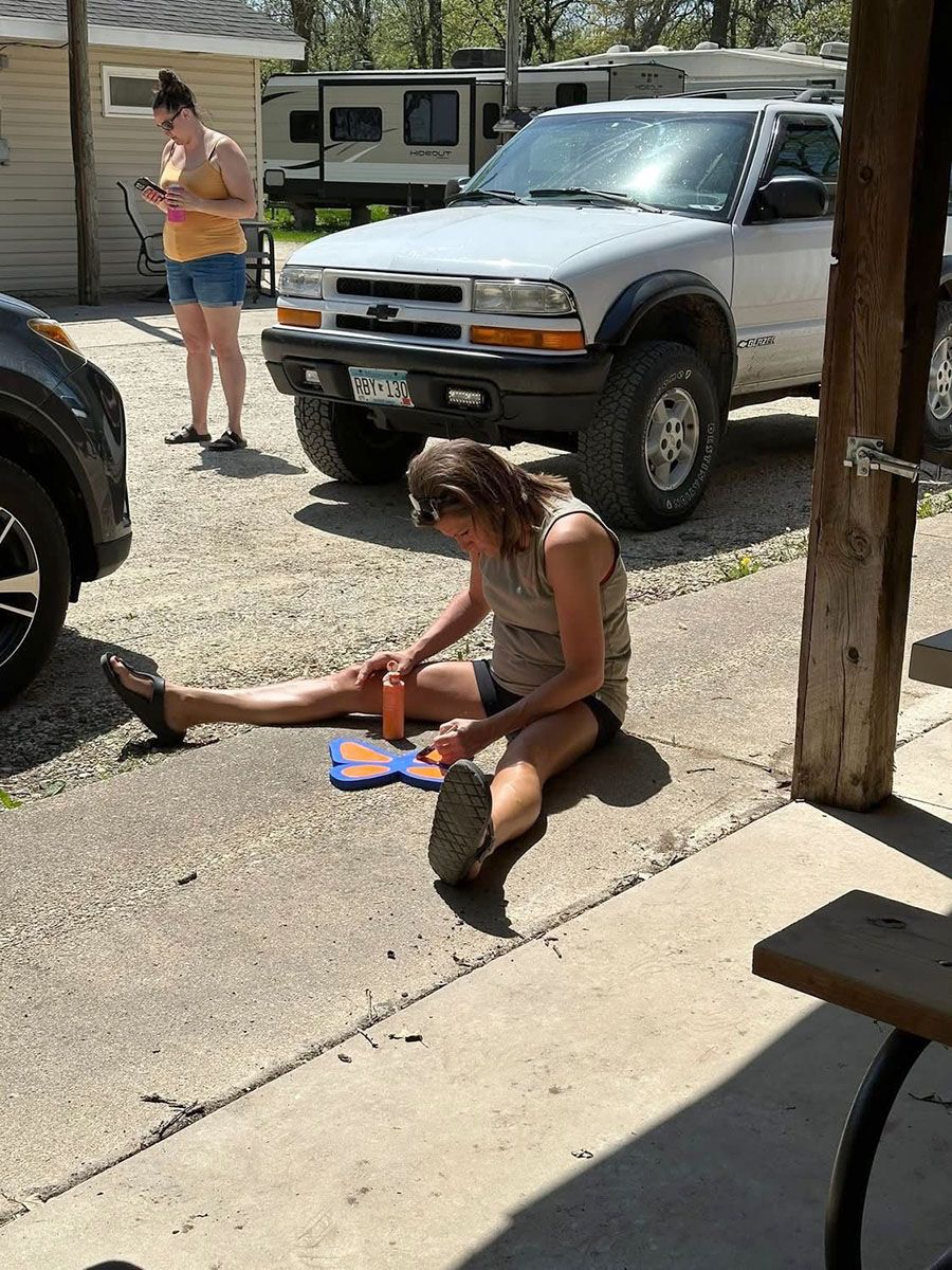 Woman seated on pavement, stretching legs