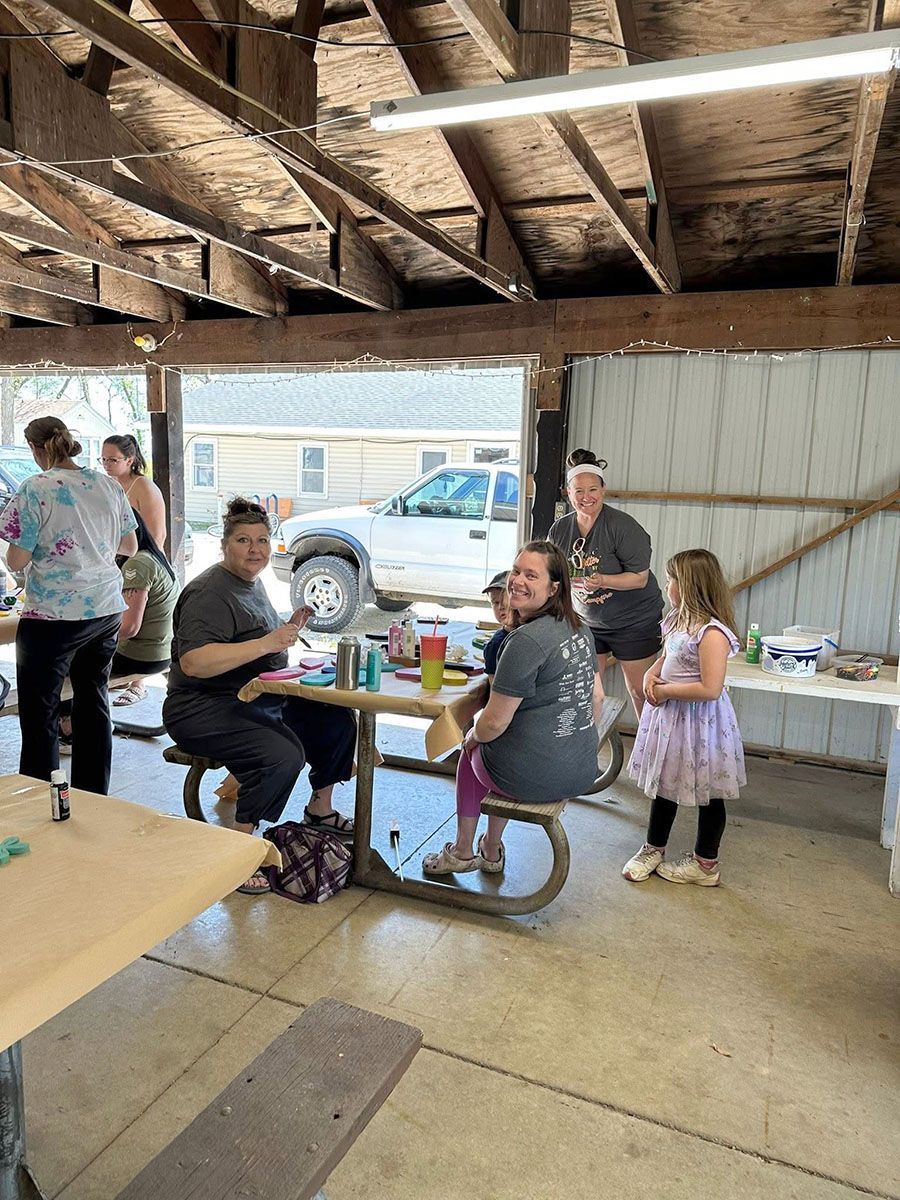 People at picnic tables under a wooden shelter