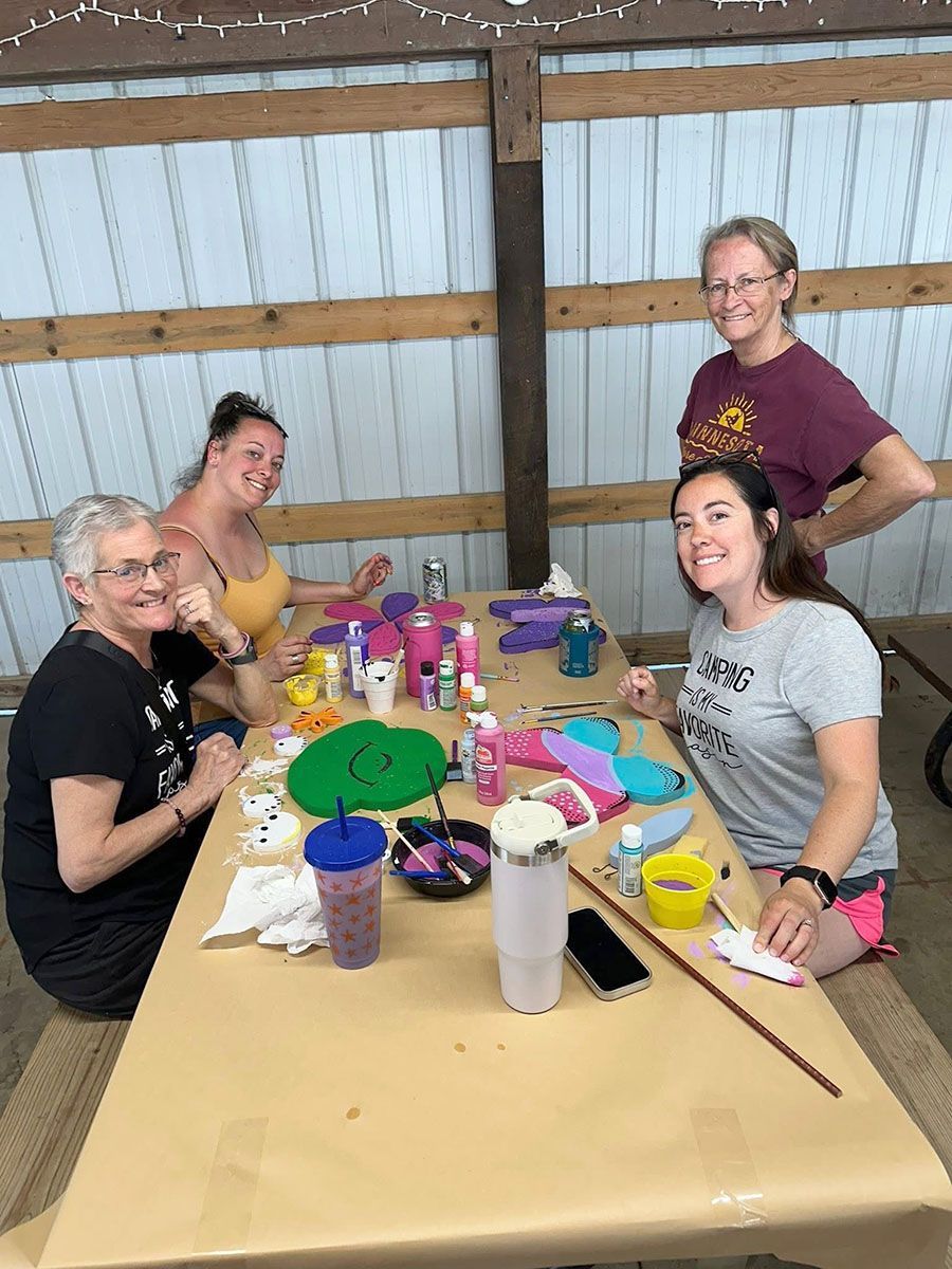 Four people craft together at a table in a shelter