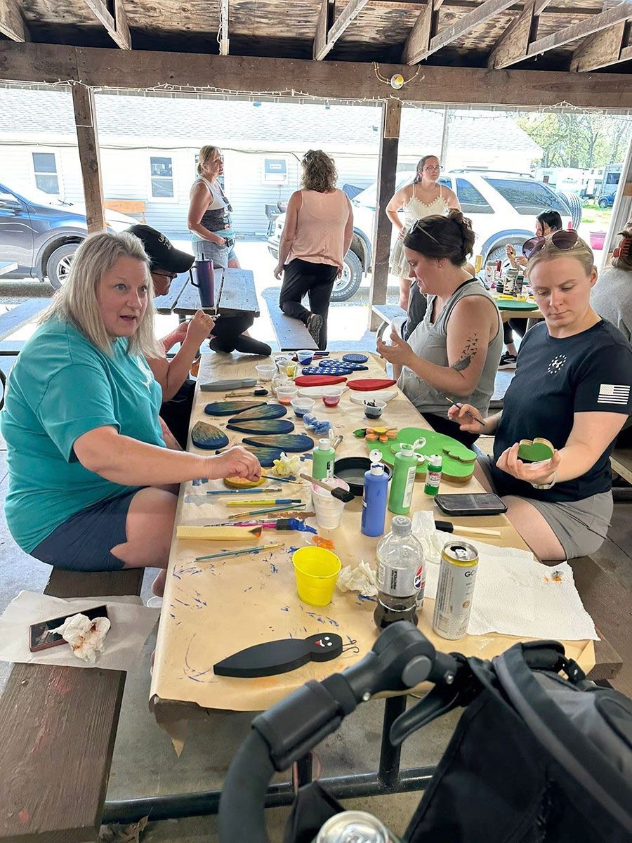 People painting crafts at a table in a park
