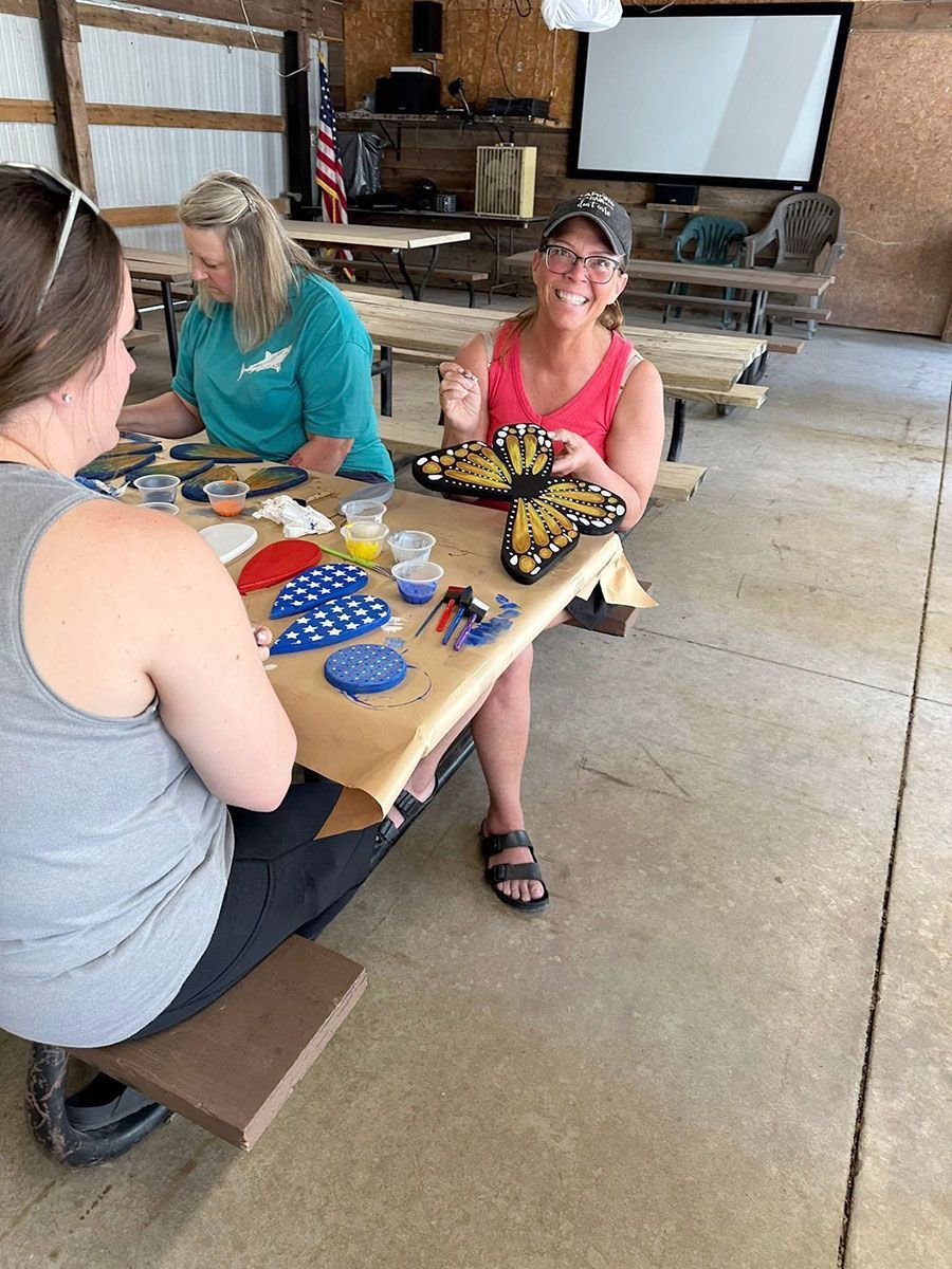 People at a craft table painting butterfly decorations
