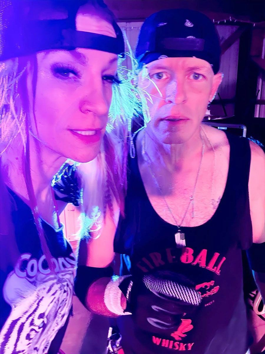 Two people in black tank tops and caps pose