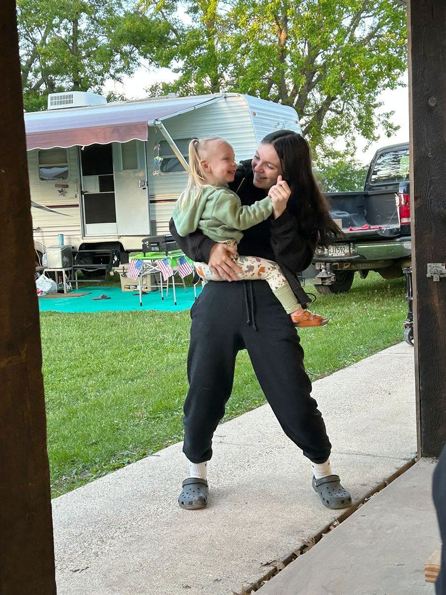 Woman holding and smiling at a small child outdoors