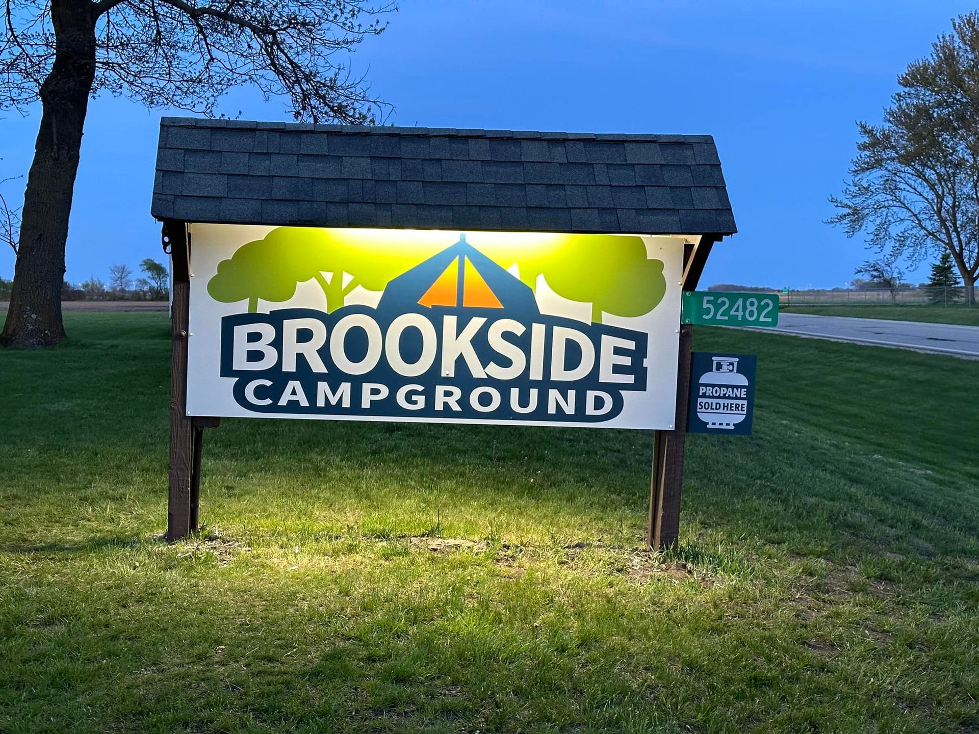 A Brookside Campground sign is lit up at night.