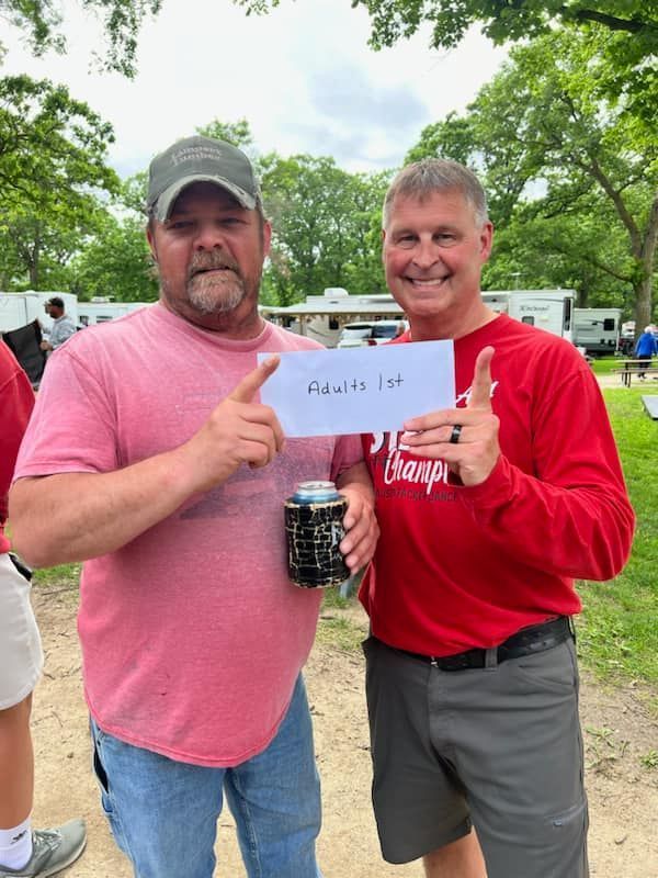 Two men standing next to each other holding a sign.