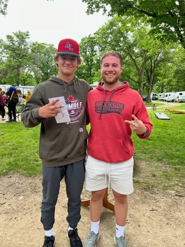 Two young men are posing for a picture in a park.