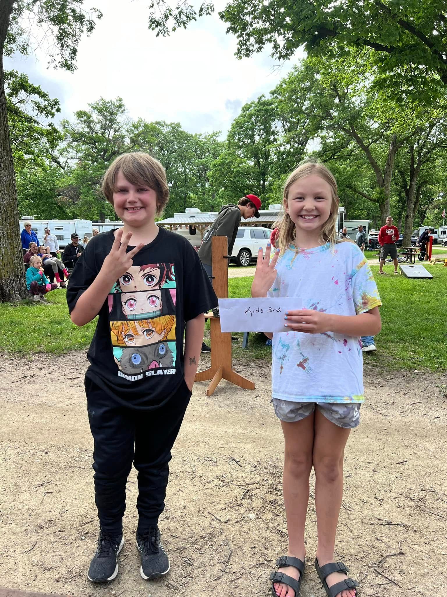 A boy and a girl are standing next to each other in a park.