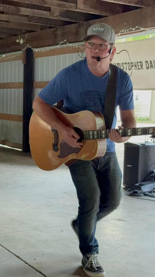 A man in a blue shirt playing an acoustic guitar.