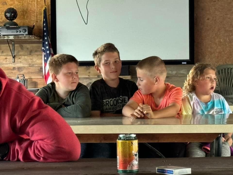 A group of children are sitting at a table with a can of soda in front of them.