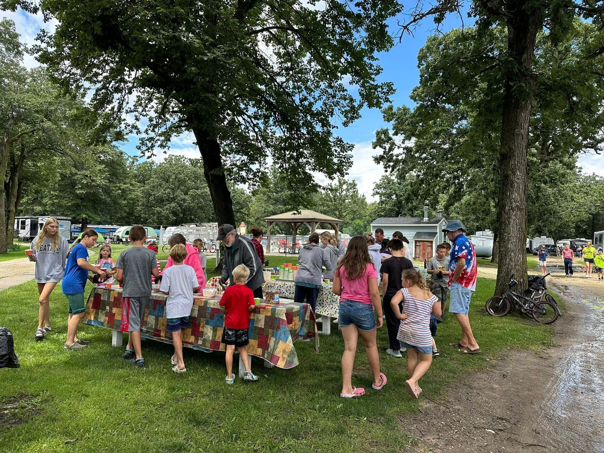 A group of people are standing around a table in a park.