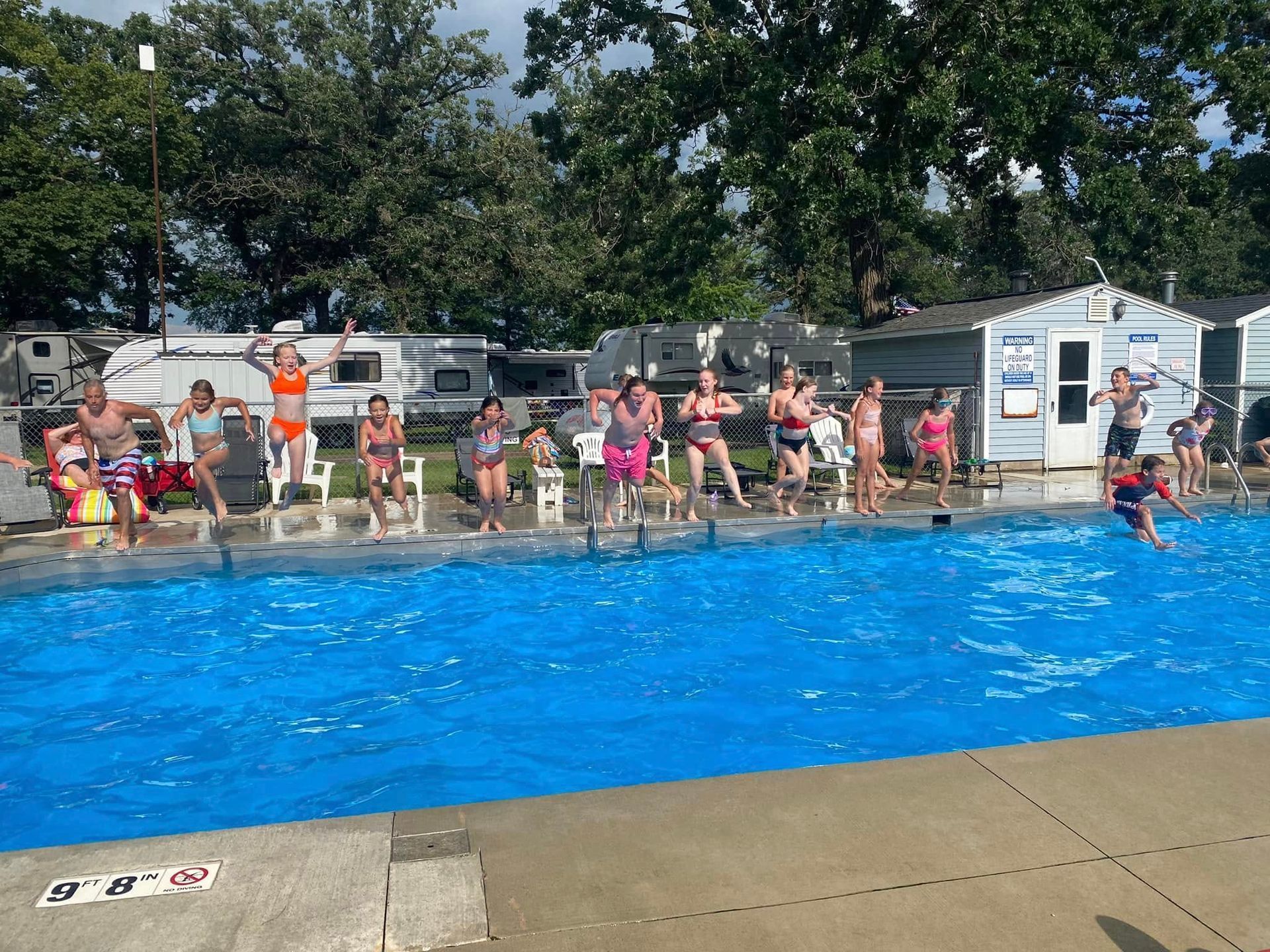 A group of people are standing around a swimming pool.