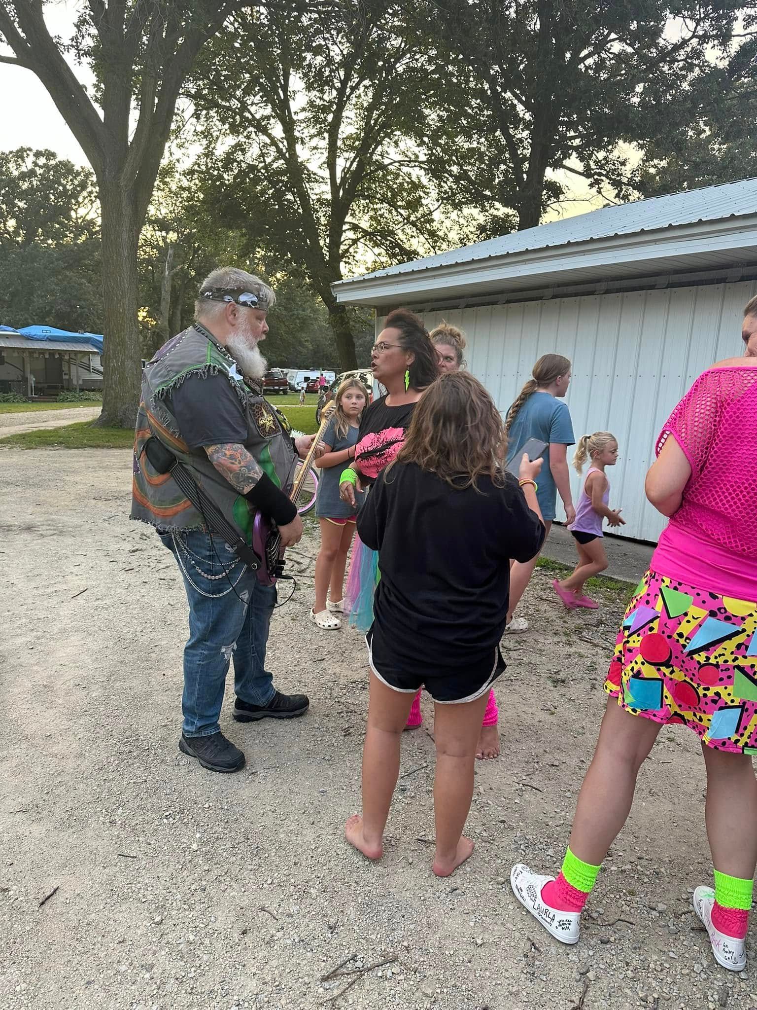 A group of people are standing in a parking lot talking to each other.