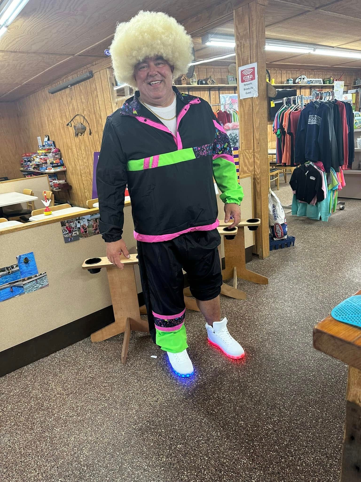 A man wearing a wig and neon clothes is standing in a store.