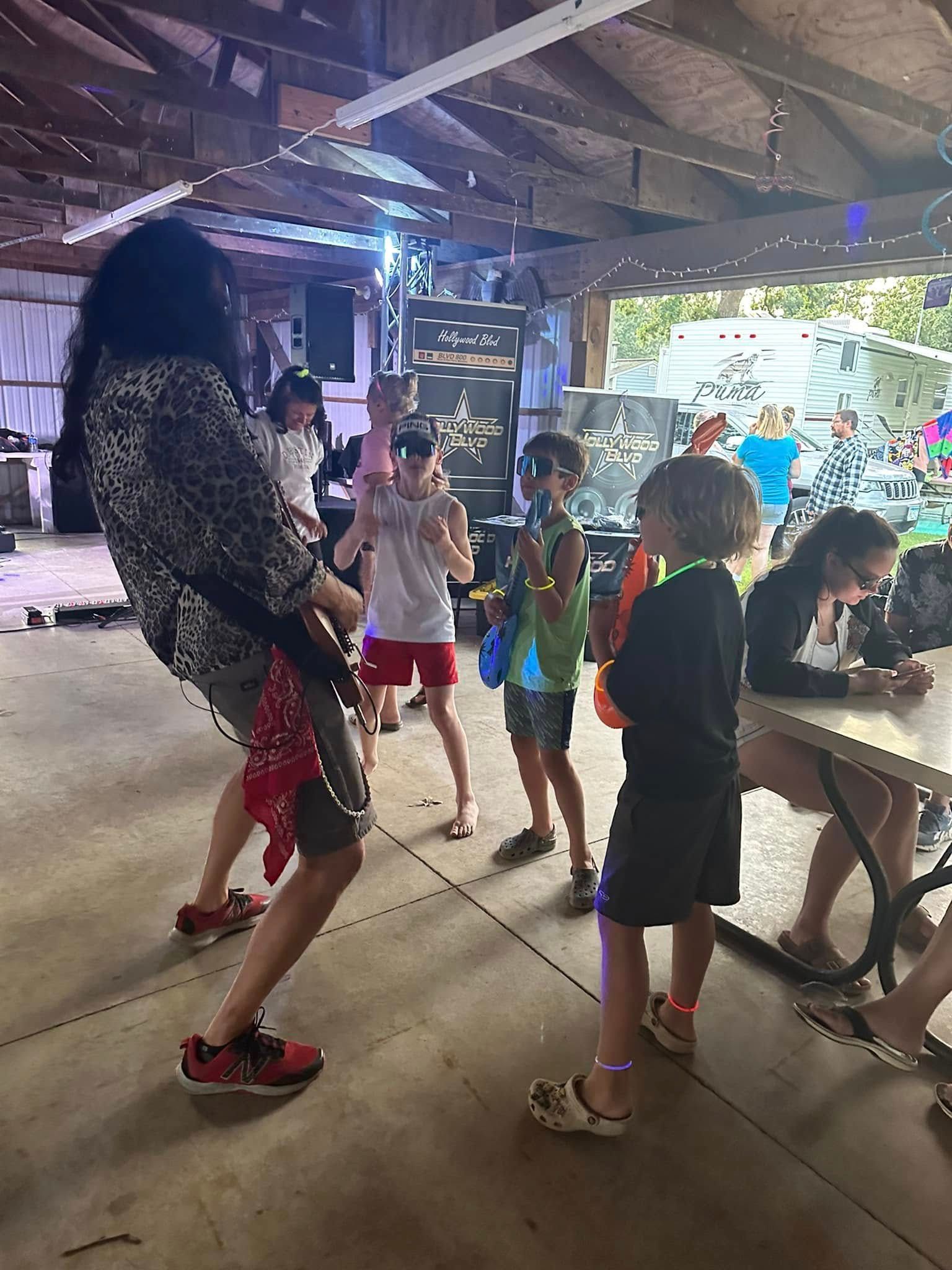 A woman is dancing with a group of children in a pavilion.