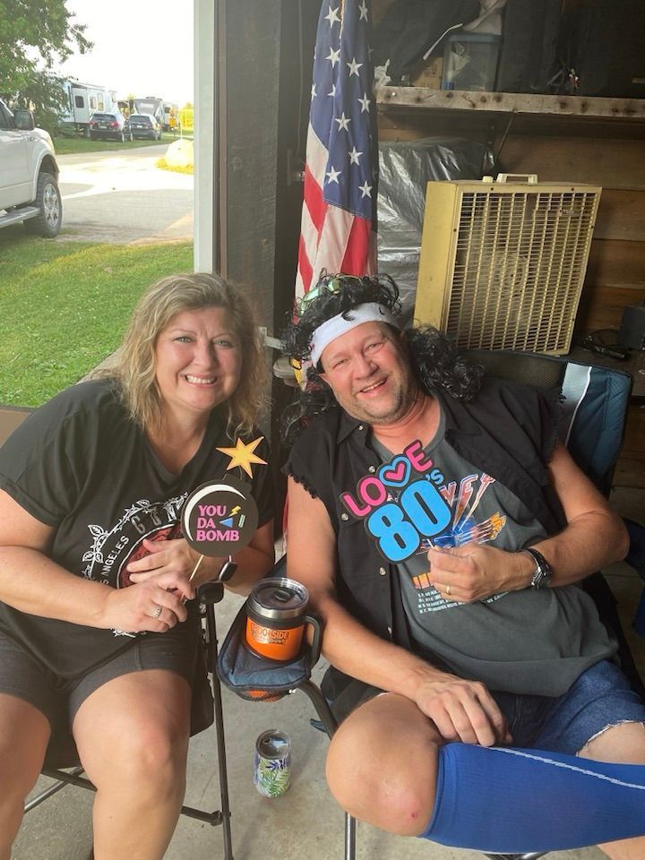 A man and a woman are sitting next to each other in front of an American flag.