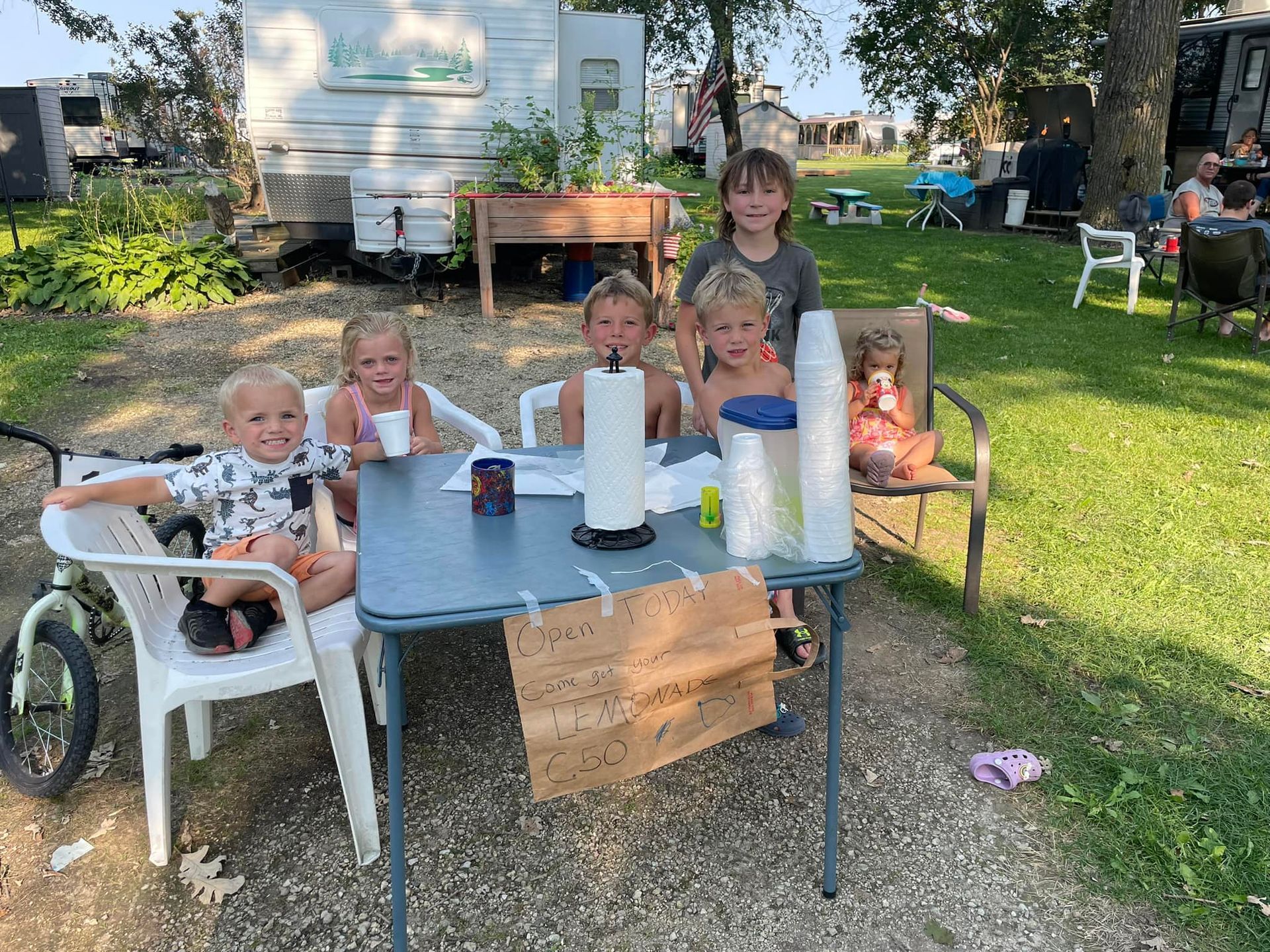 A group of children are sitting around a table in a park.