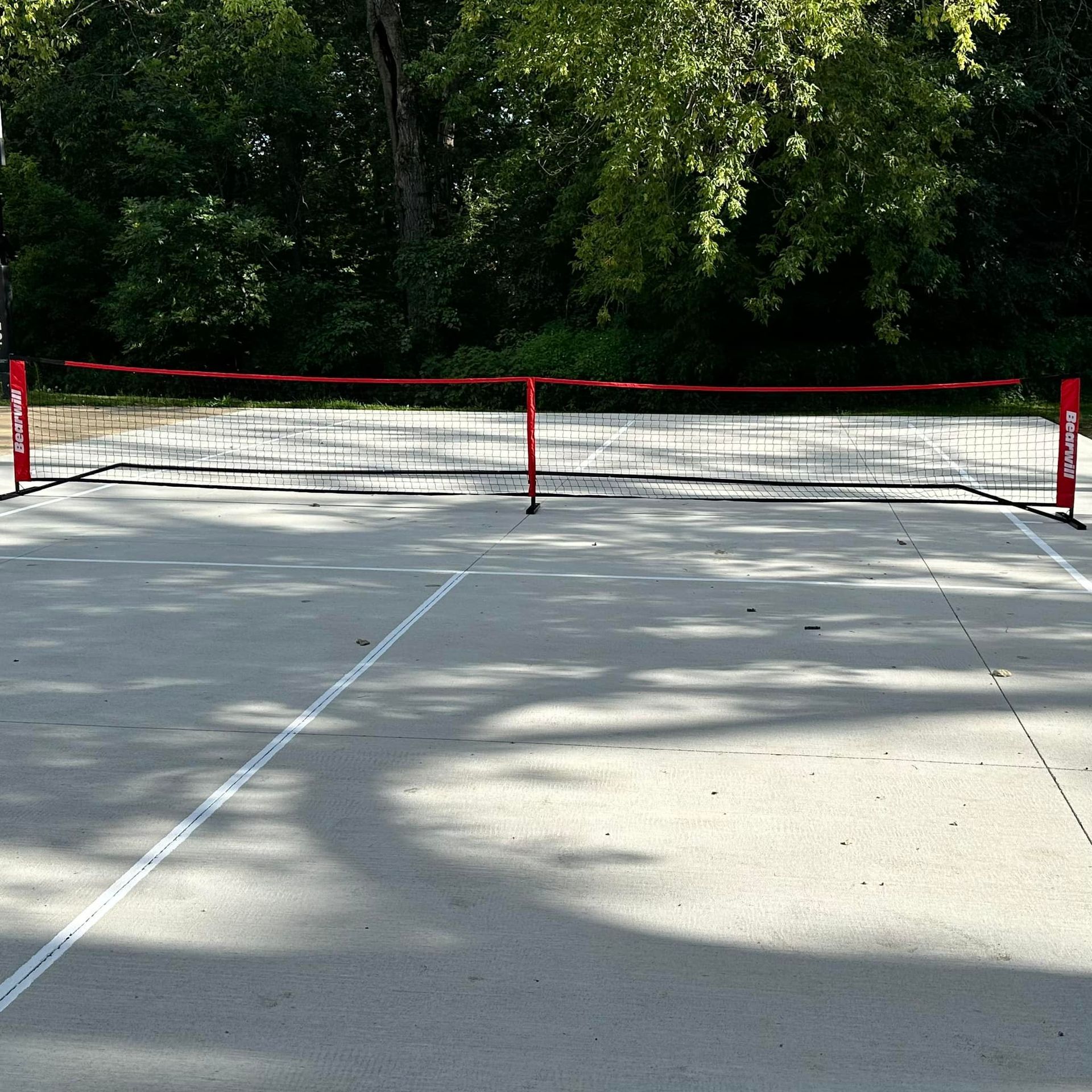 A tennis court with a red net and white lines.