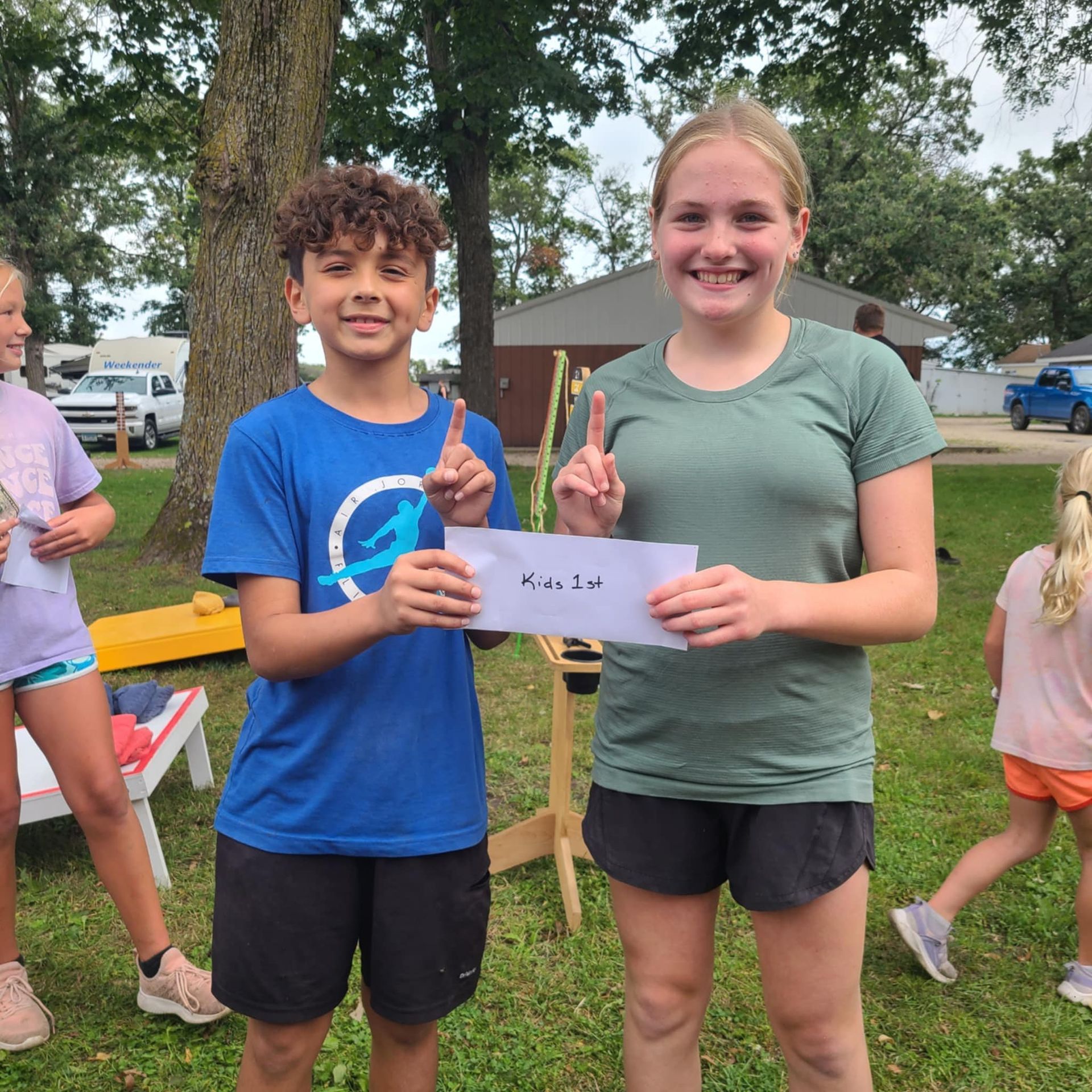 A boy and a girl standing next to each other holding a paper that says 2nd.