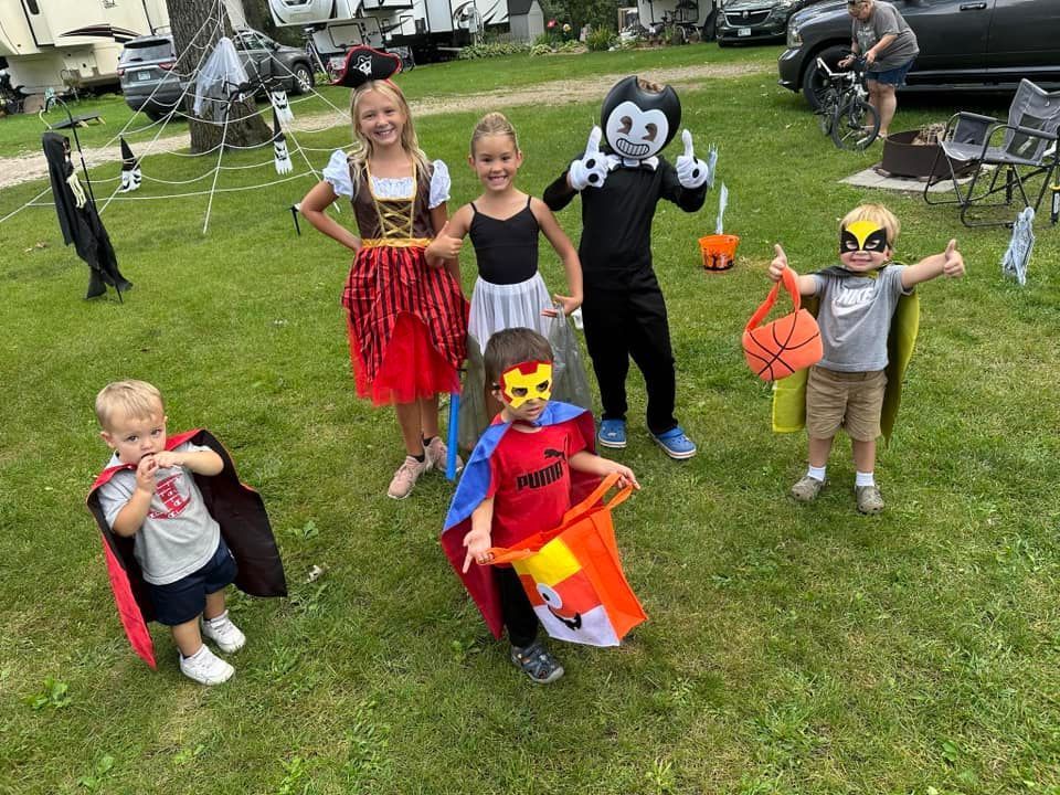 A group of children dressed in costumes are standing in the grass.