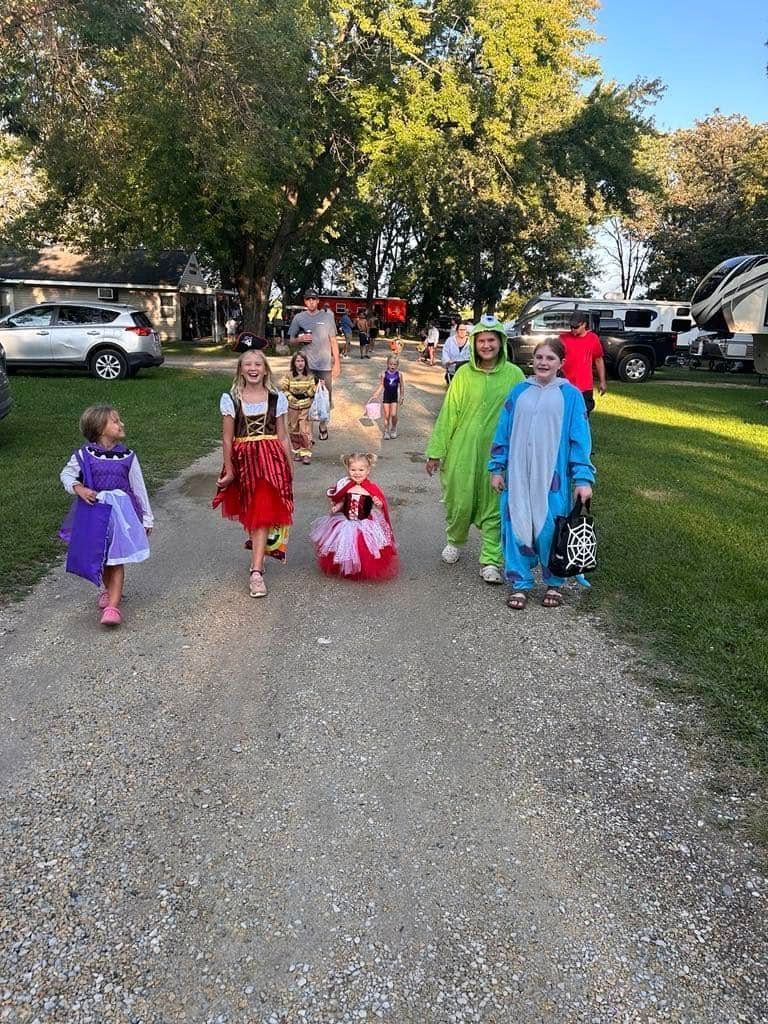 A group of children in costumes are walking down a dirt road.