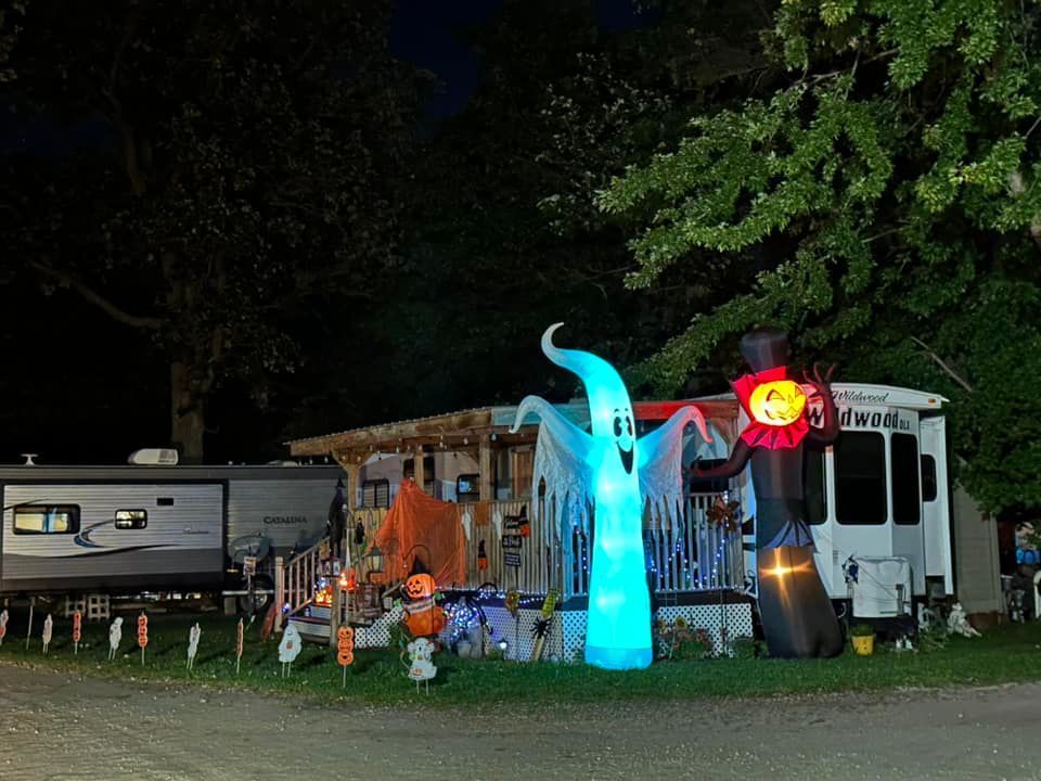 An RV parked in front of a house decorated for Halloween.