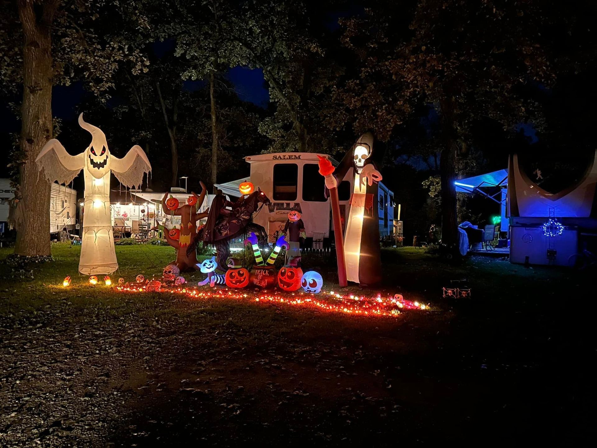 A yard decorated for Halloween with pumpkins, ghosts, and skeletons.