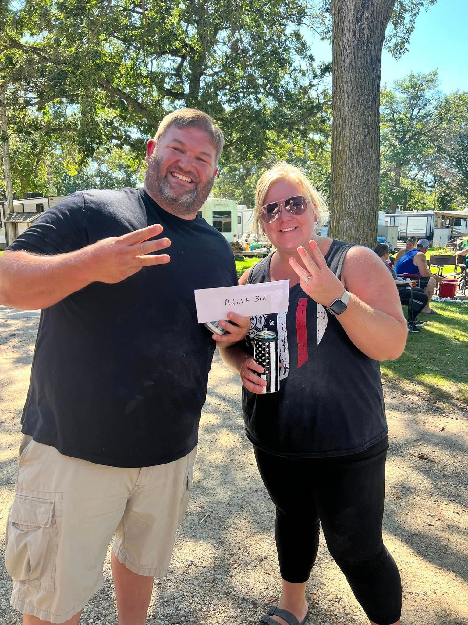 A man and a woman are standing next to each other in a park.