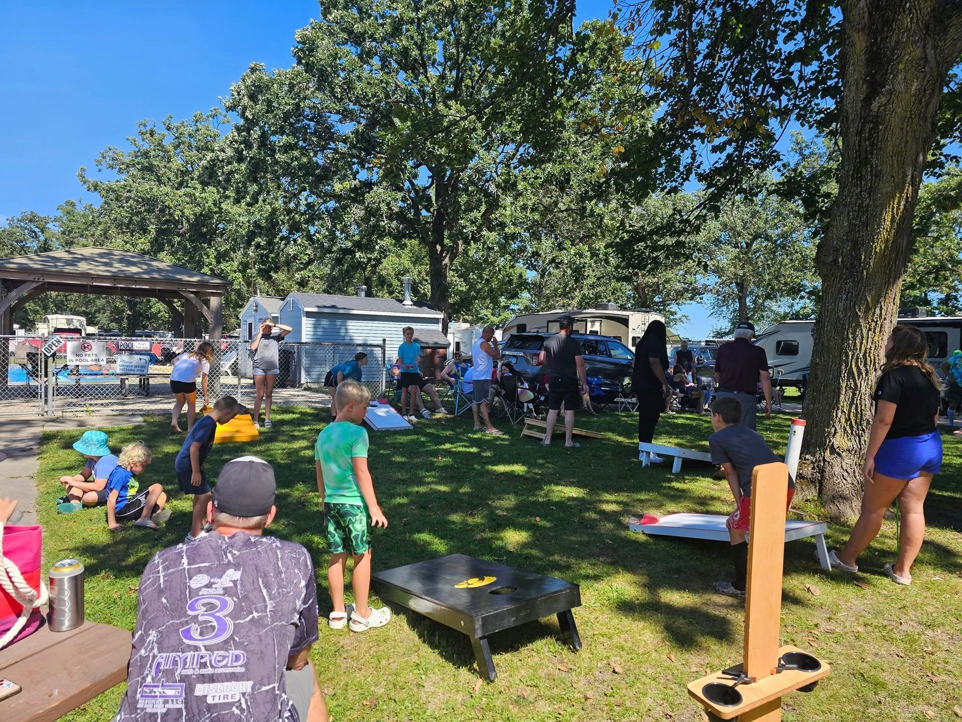 A group of people are playing cornhole in a park.