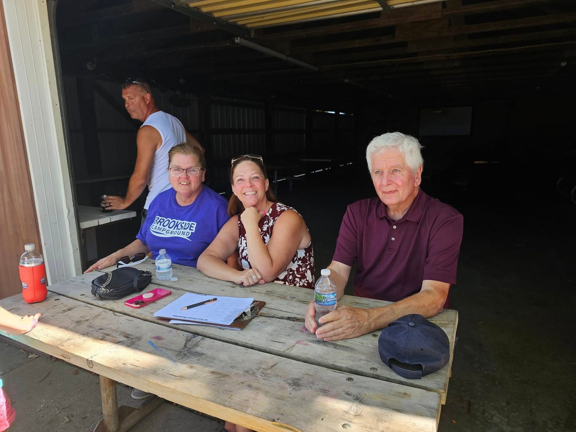 A group of people are sitting at a wooden picnic table.