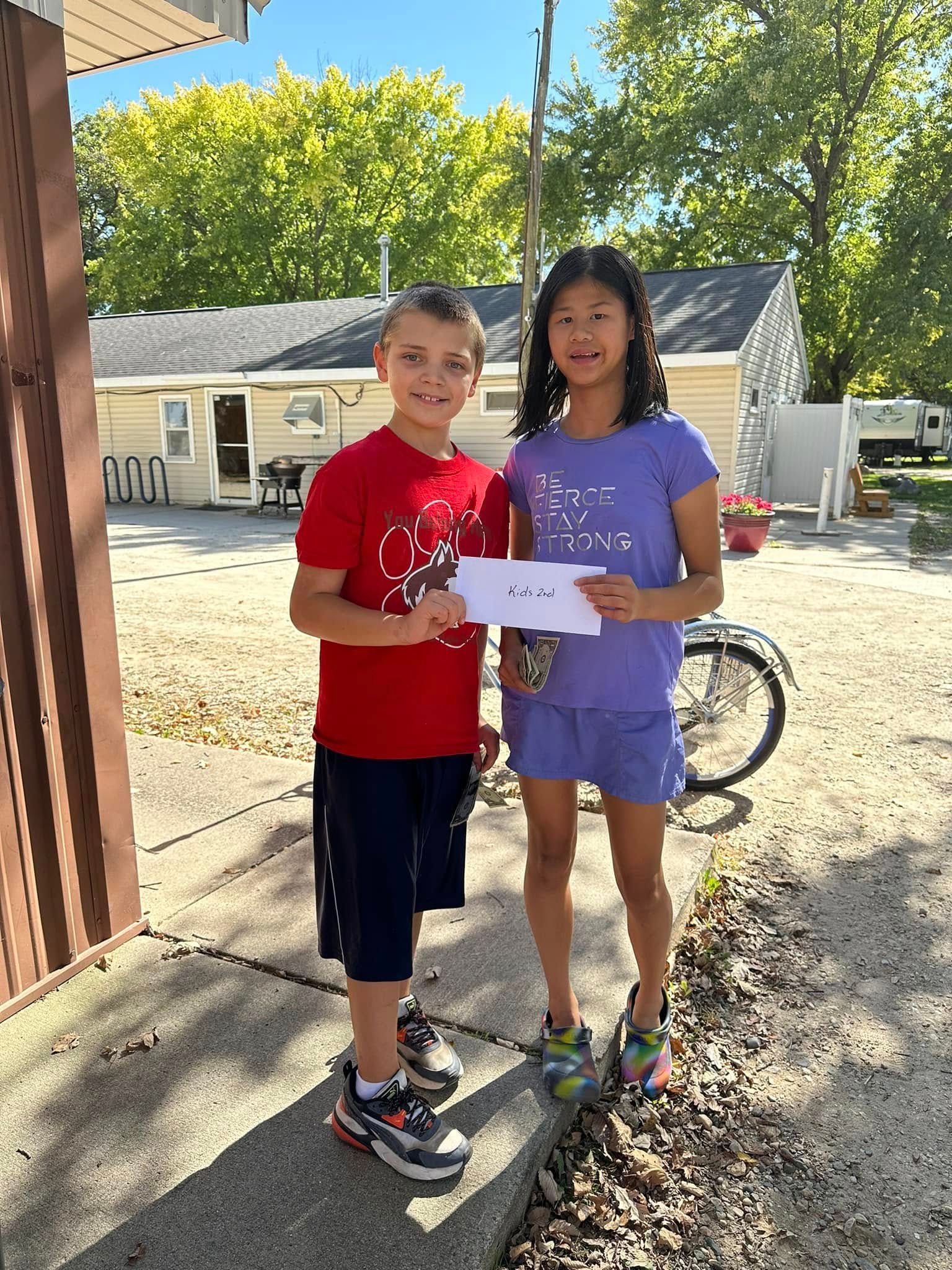 A boy and a girl are standing next to each other on a sidewalk