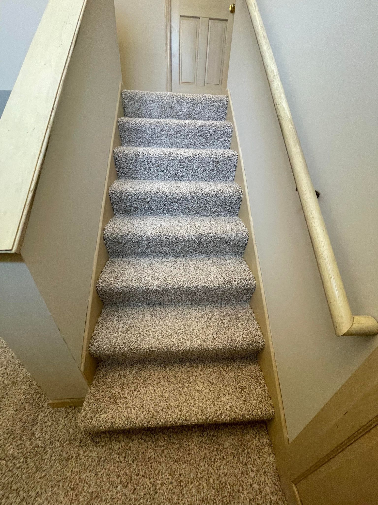 Staircase with carpeted steps and a handrail. Beige and gray color scheme.